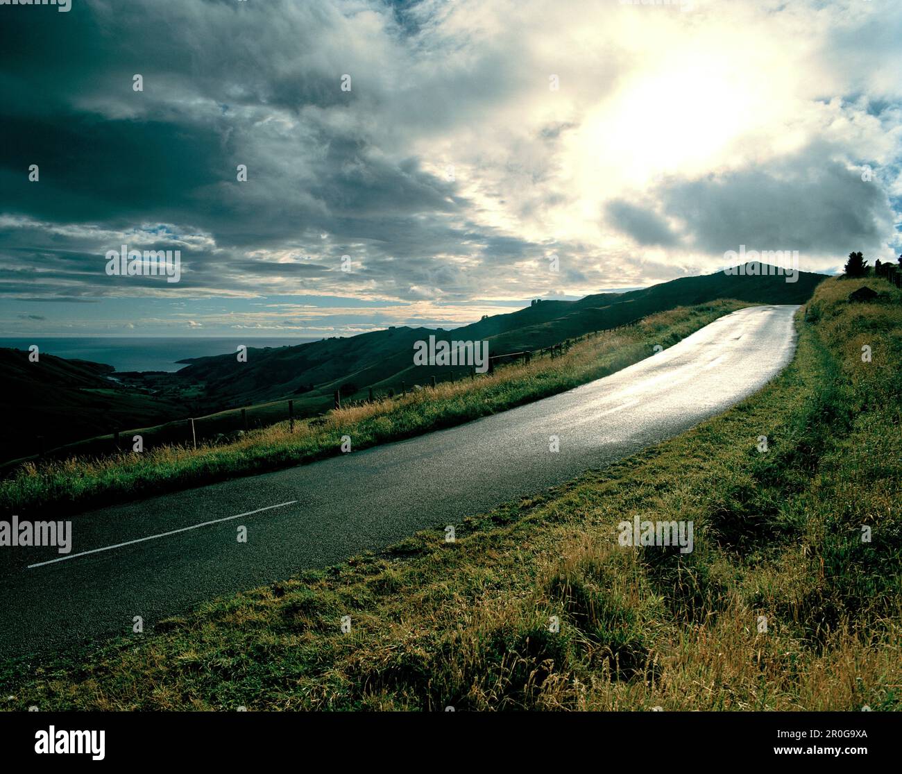 Summit Road und Blick über Okains Bay unter grauen Wolken, Banks Peninsula, South Island, Neuseeland Stockfoto