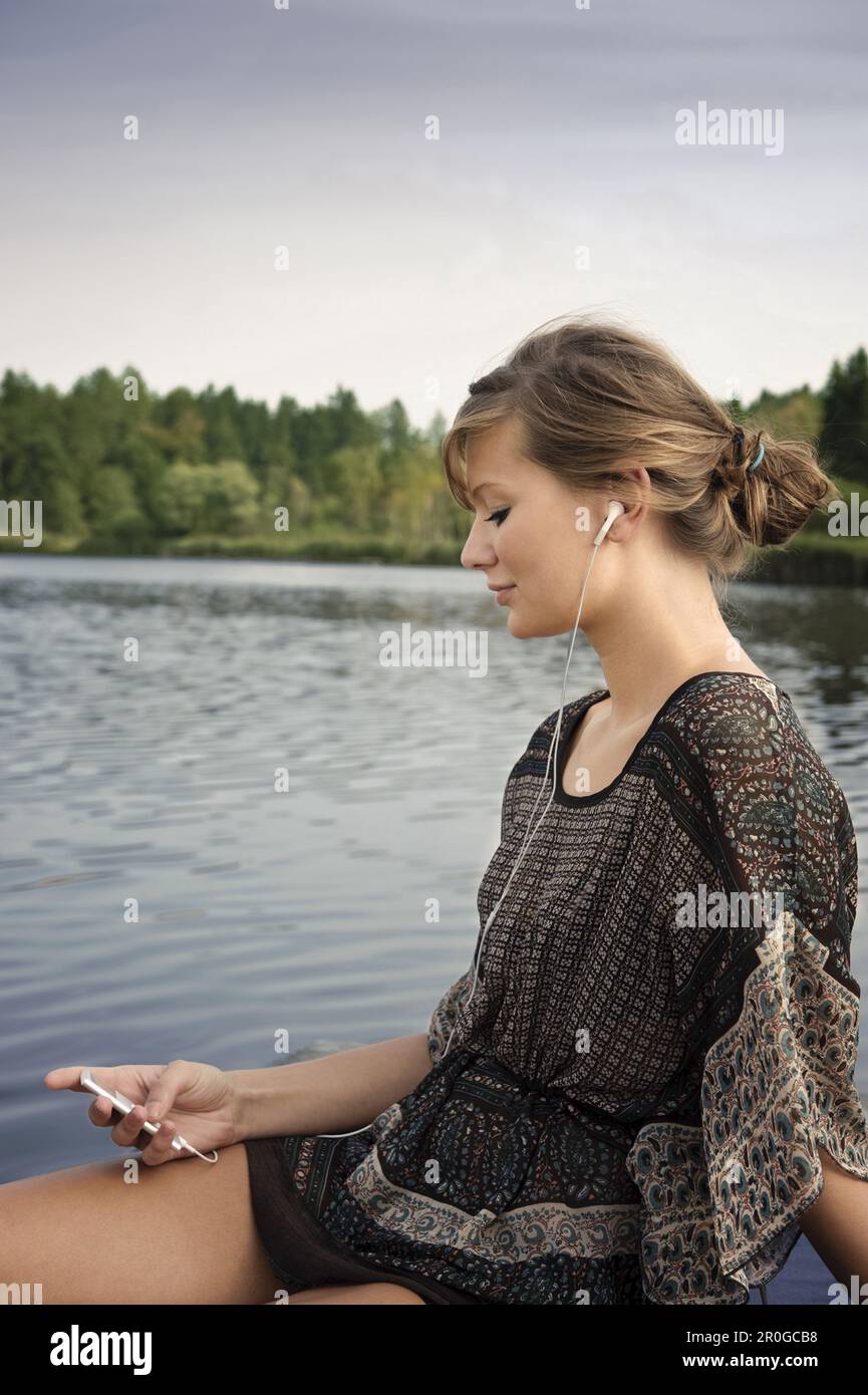 Junge Frau, die Musik am See Starnberg in Bayern hört Stockfoto