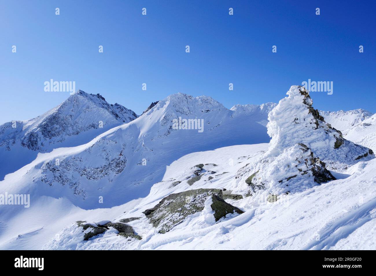 Winterlandschaft mit schneebedecktem Cairn über dem Vogelmaier-Ochsenkar-Kees-Gletscher, dem hohen Sonnblick, dem Rauriser-Tal und der Goldberggruppe Stockfoto
