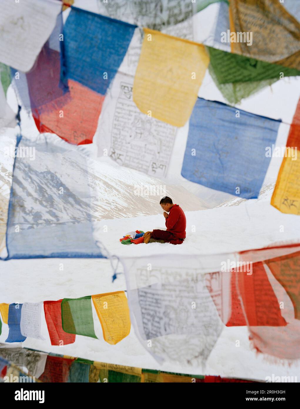 Mönch Wangyal betet auf Khardung La, weiht Gebetsflaggen, den höchsten befahrbaren Pass der Welt und Straße 5570m m über dem Meeresspiegel, nördlich von Leh, Ladakh, Stockfoto