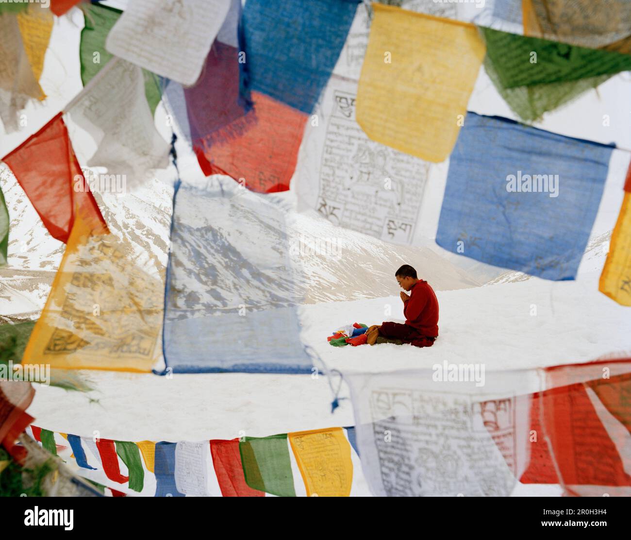 Mönch Wangyal betet auf Khardung La, weiht Gebetsflaggen, den höchsten befahrbaren Pass der Welt und Straße 5,570m m über dem Meeresspiegel, nördlich von Leh, Ladakh Stockfoto