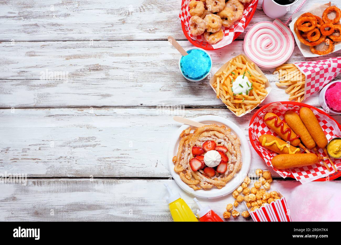 Karneval-Thema, Essensseite mit weißem Holzhintergrund. Über der Ansicht mit Kopierbereich. Sommermesse-Konzept. Corn Dogs, Trichterkuchen, Zuckerwatte und Stockfoto