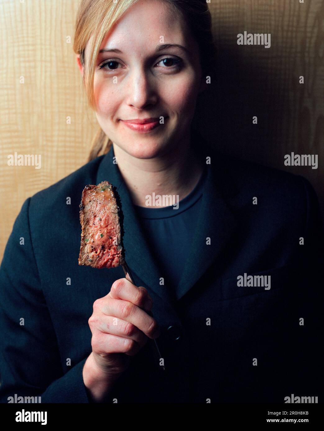 USA, Kalifornien, Los Angeles, Porträt einer jungen Kellnerin mit einem Stück Steak auf der Gabel am Schnitt Restaurant. Stockfoto