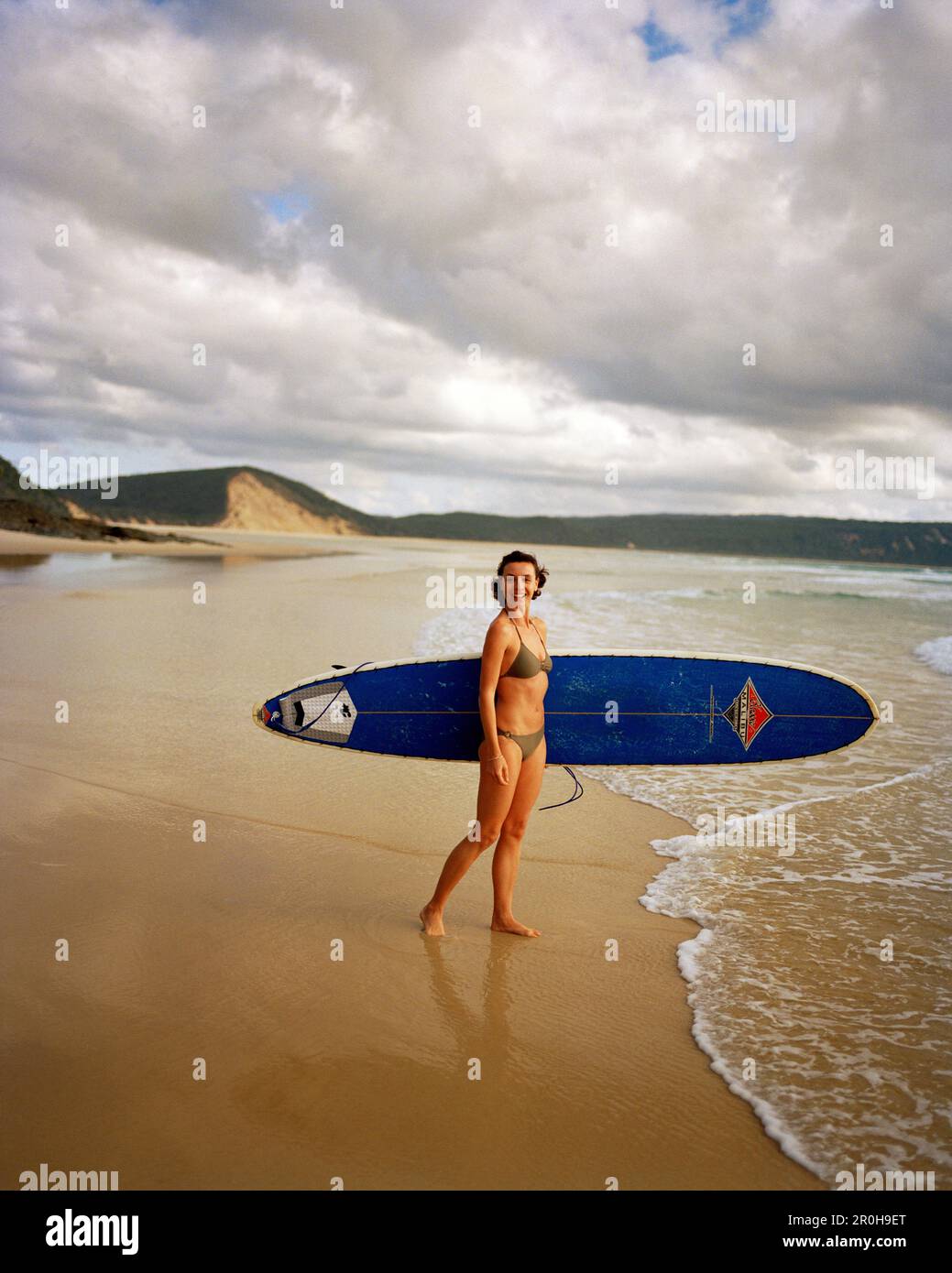 AUSTRALIEN, Queensland, Noosa Heads, Porträt einer Surferin, die lächelt, bevor sie ins Wasser kommt, 40 Mile Beach Stockfoto