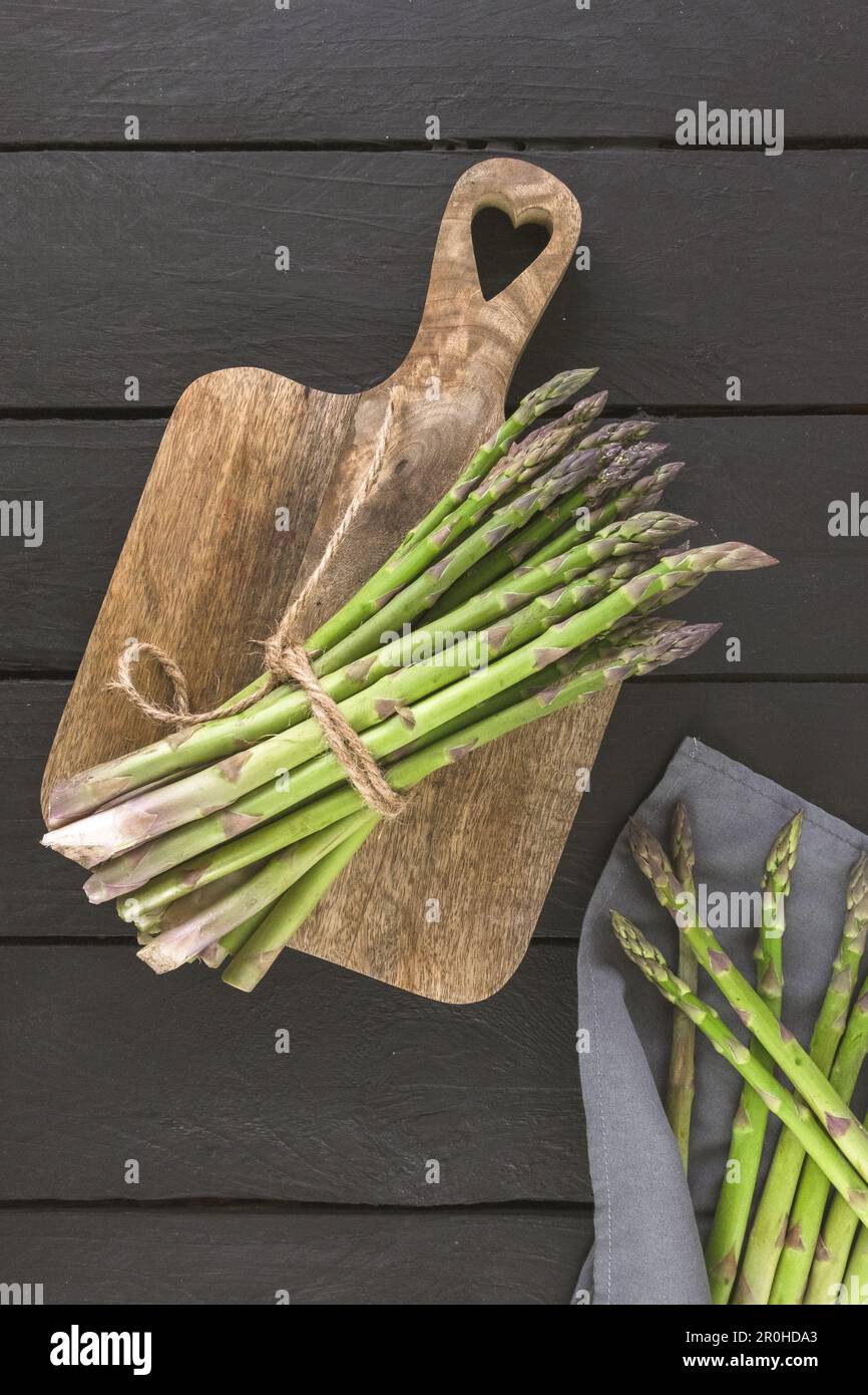 Bänke aus frischem grünen Spargel auf Holzhintergrund, Draufsicht, vertikales Foto Stockfoto