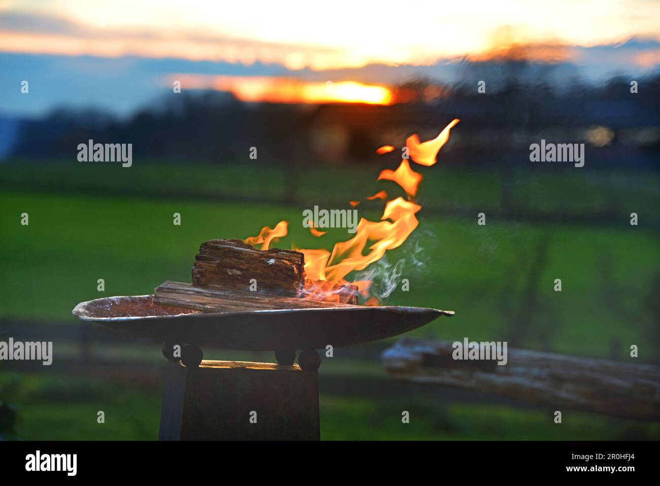 Brennende Feuerschale in einem Garten bei Sonnenuntergang, Deutschland Stockfoto