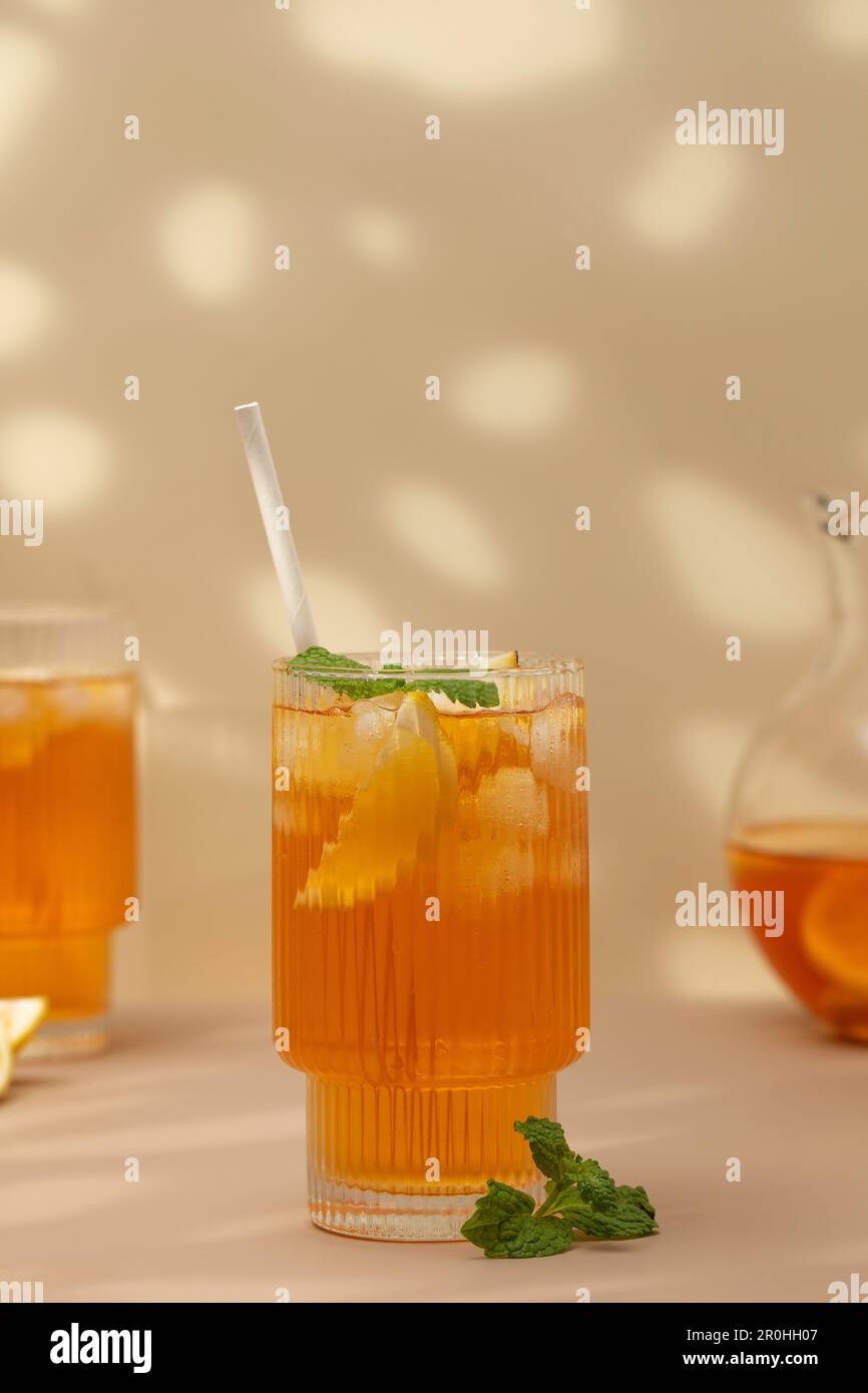 Ein Glas kalten Tee, Eiswürfel, Zitronenscheiben und einen Pfefferminzzweig. Kühle Sommergetränke. Stockfoto