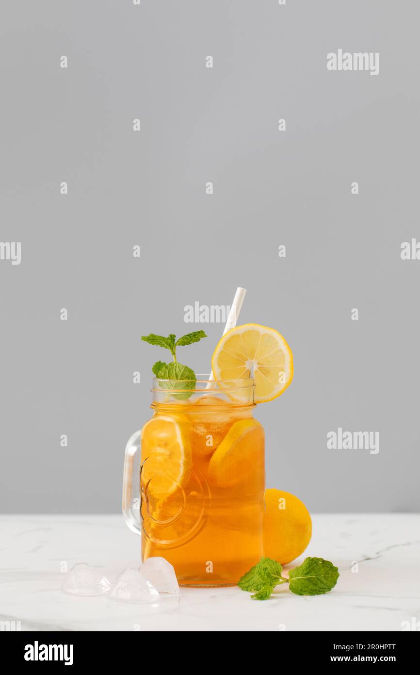 Ein Glas kalten Tee, Eiswürfel, Zitronenscheiben und einen Pfefferminzzweig. Kühle Sommergetränke. Stockfoto