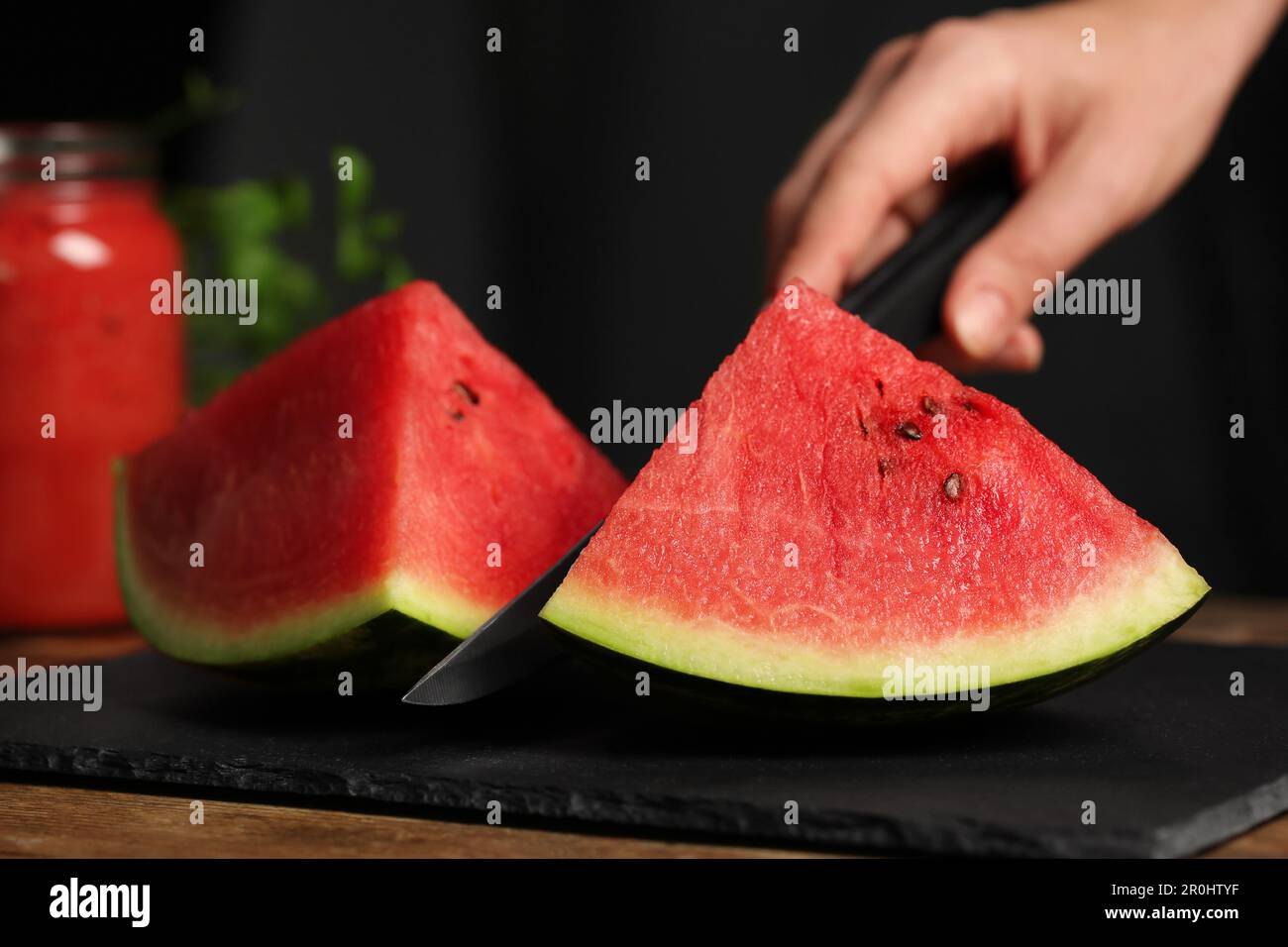 Frau schneidet köstliche Wassermelone auf Schieferbrett, Nahaufnahme Stockfoto