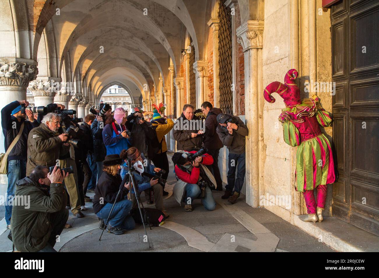 Venezianischer Karneval, Tourismus, Masken, Harlequin, Narren, Kostüm, Posen, Armee von Fotografen, Arkade des Dogenpalastes, Venedig, Italien Stockfoto