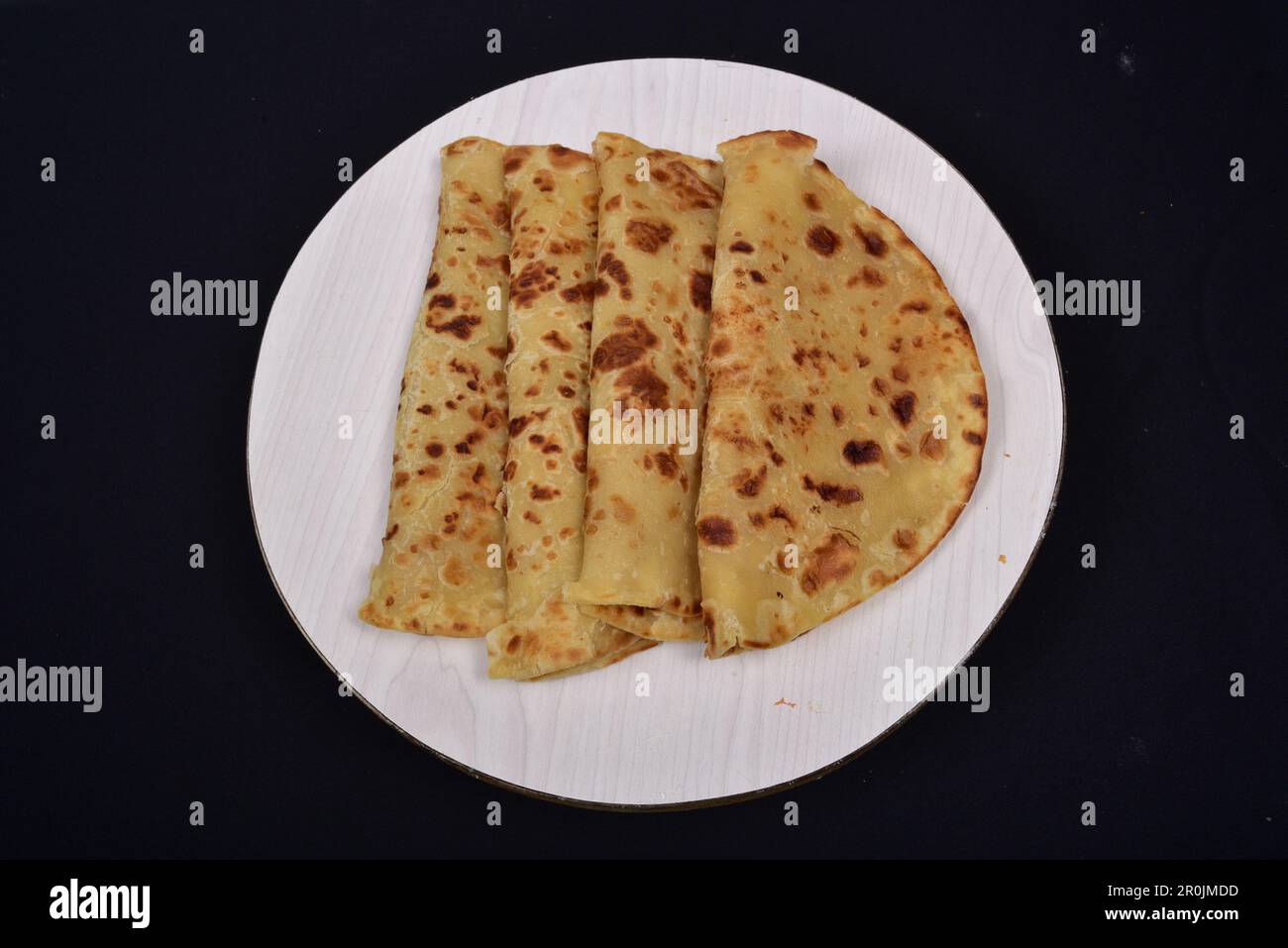 Afrikanische Chapati, gefaltet in Hälften auf schwarzem Hintergrund Stockfoto