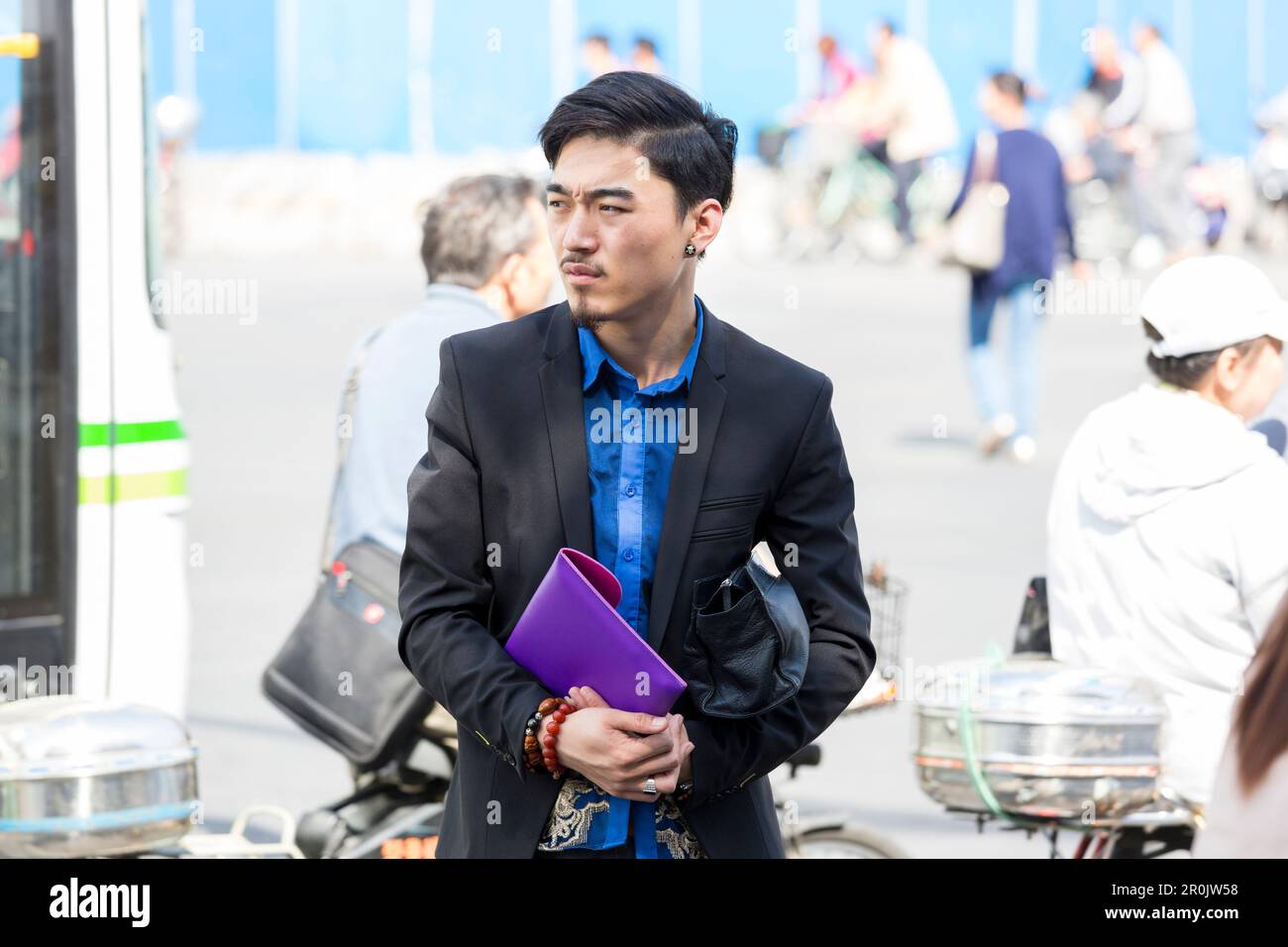 Junger, gutaussehender Mann auf der Straße, wartet auf Bus, Ohrring, schwarze Jacke, blaues Hemd, Shanghai, China, Asien Stockfoto