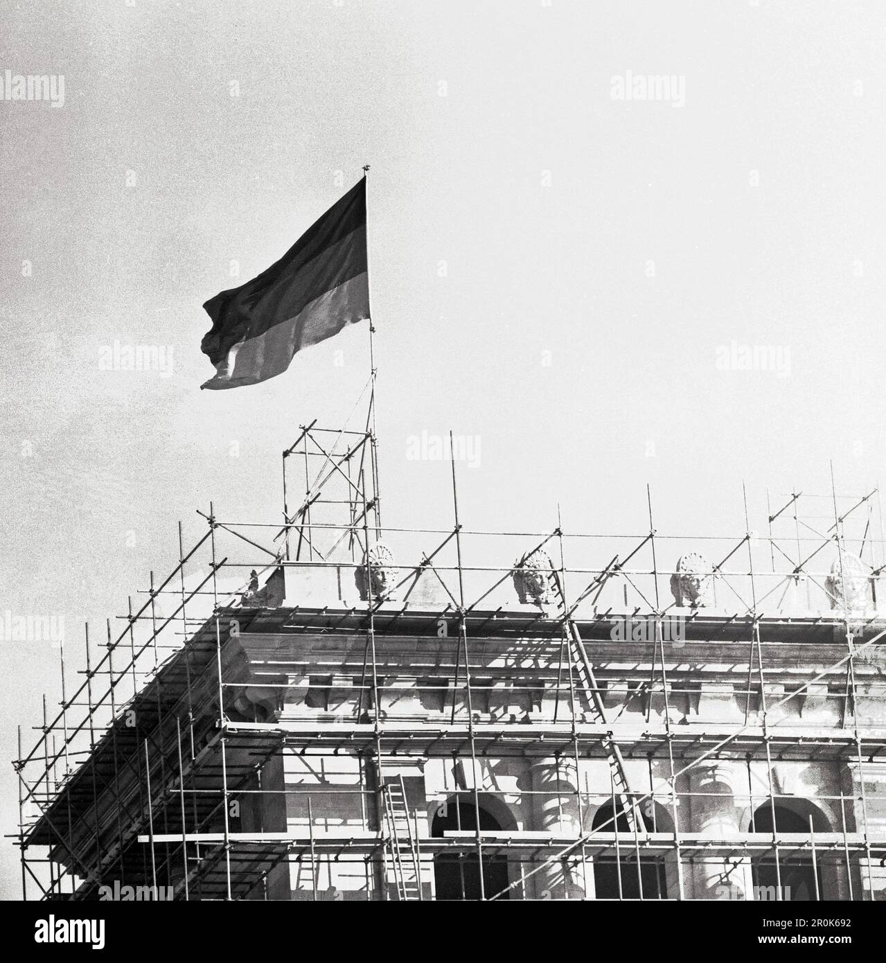 Auf dem Reichstag weht ab heute die deutsche Flagge - Original-Bildunterschrift: Als Anwort auf die unerhörte Provokation der Zonenmachthaber, die auf den S-Bahnhöfen in Westberlin die Sowjetzonenfahne gehisst hatten, hat heute auf dem Reichstag die deutsche schwarze Flagge rot Gold aufgezogen, Berlin, Deutschland 1959. Stockfoto