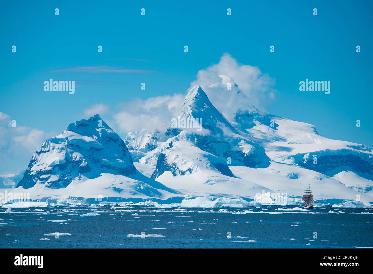 Segelrinde Europa inmitten von Eisschollen und Eisbergen mit schneebedeckten Bergen dahinter Stockfoto
