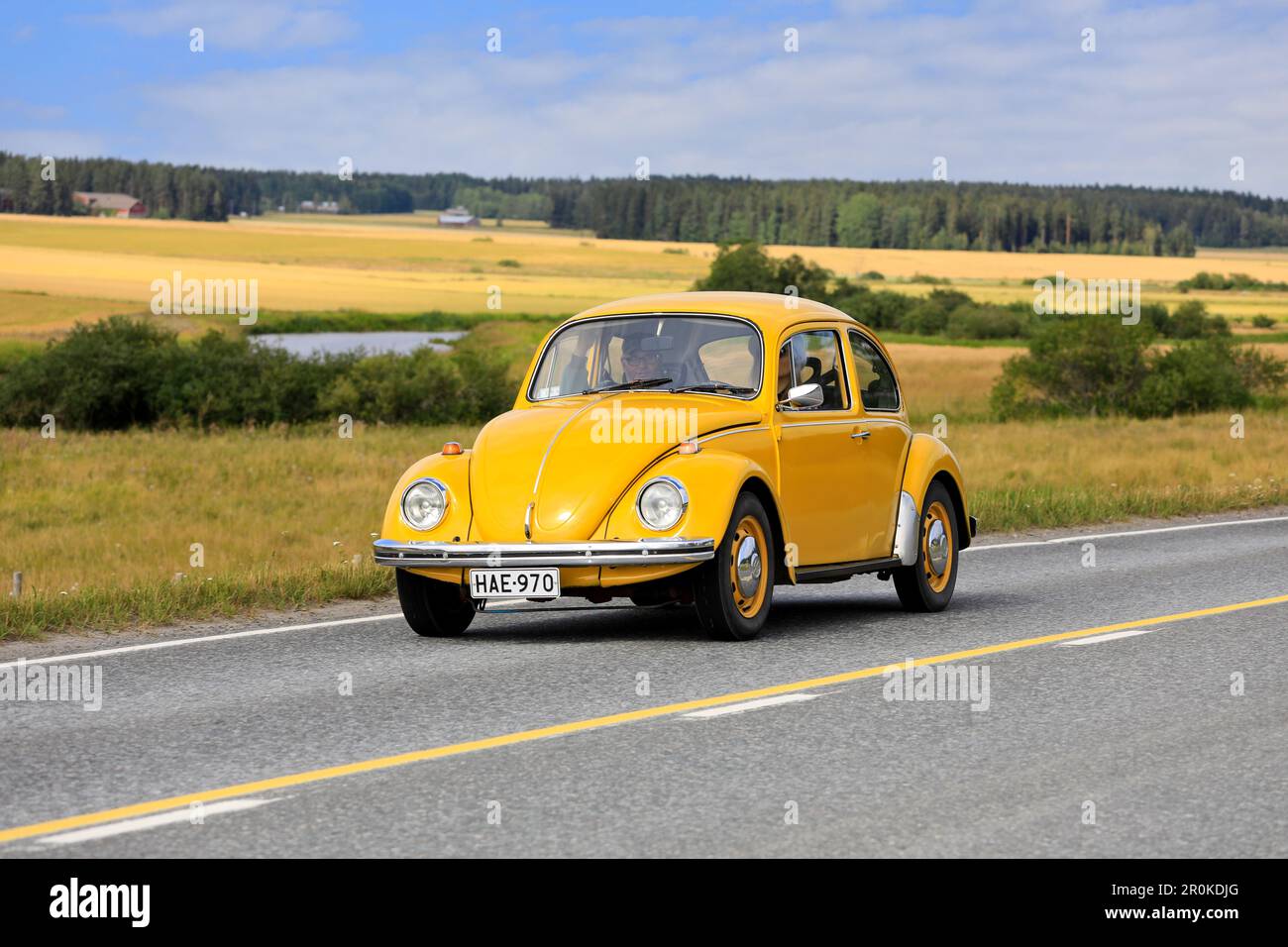 Gelber Volkswagen Käfer, offiziell Volkswagen Typ 1, fährt auf der Maisemaruise 2019-Autofahrt entlang der Landstraße. Vaulammi, Finnland. 3. August 2019. Stockfoto