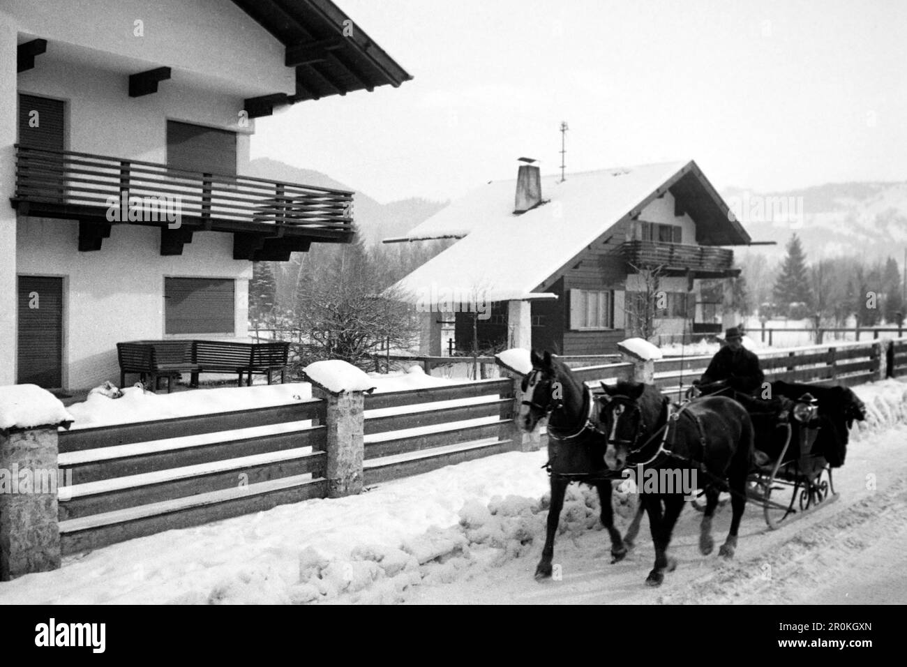 Pferdeschlitten vor regionaltypische Wohnhäuser, Garmisch Partenkirchen 1936. Pferdeschlitten vor typischen regionalen Häusern, Garmisch Partenkirchen 1936. Stockfoto