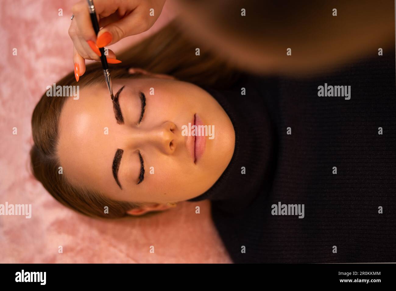 Kosmetologe, der Farbstoff auf die Augenbraue eines weiblichen Kunden anwendet Stockfoto