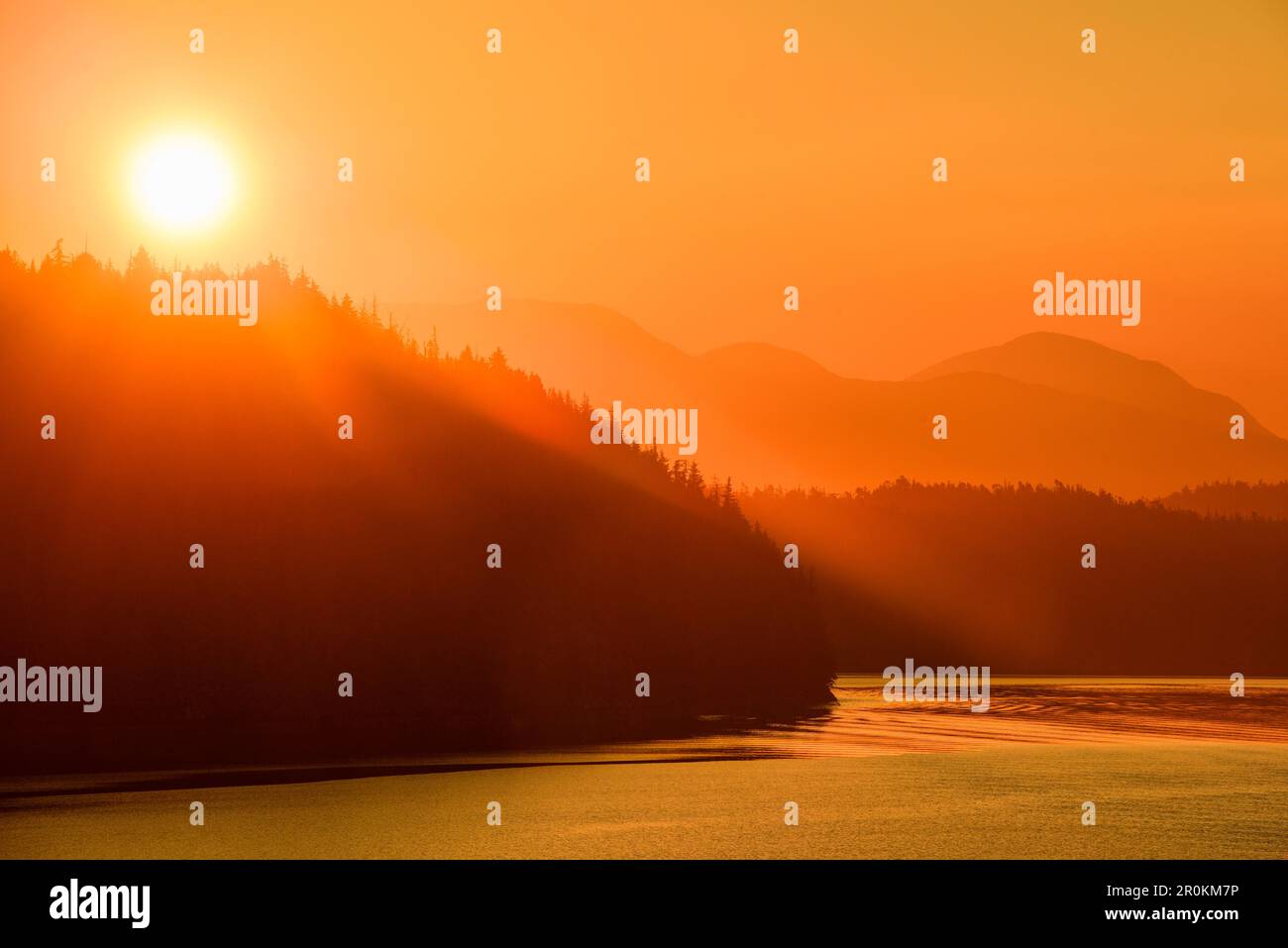 Die goldene Sonne erhebt sich hinter den Bergen, die vom Expeditionsschiff MS Bremen (Hapag-Lloyd Cruises), Milbanke Sound, Inside Passage, zwischen Denny, aus gesehen werden Stockfoto