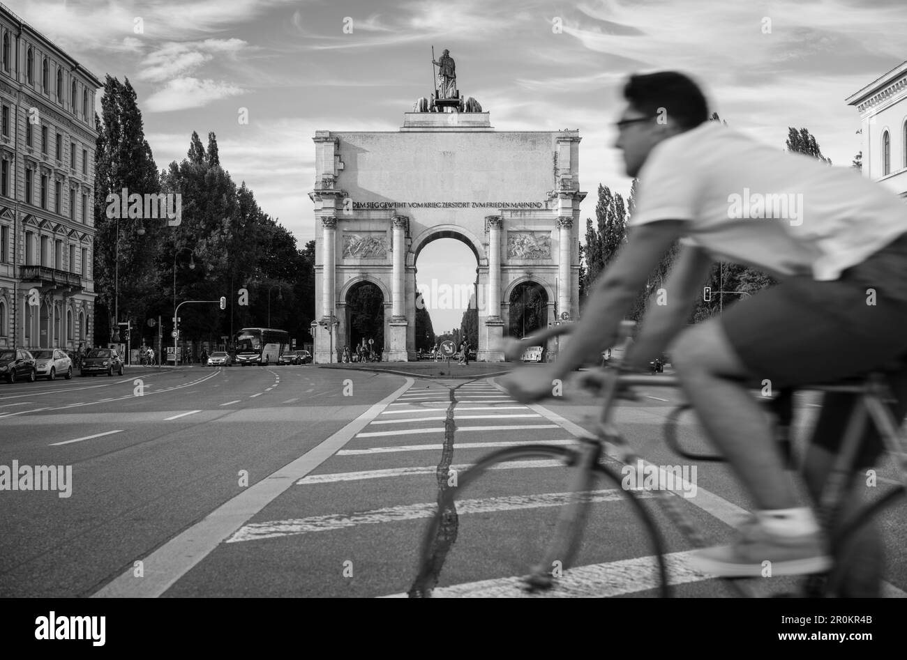 Straßenszene vor Siegestor, ein Radfahrer, der die Straße überquert, München, Oberbayern, Deutschland Stockfoto
