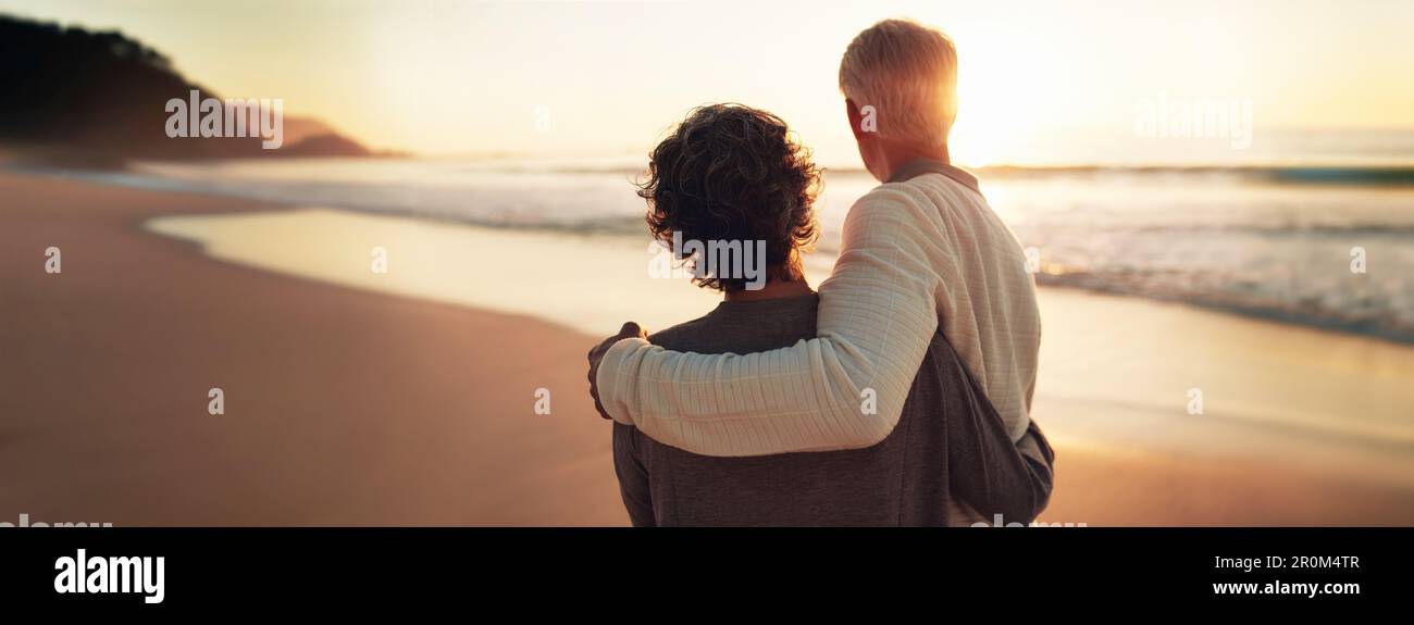 Ein glückliches Seniorenpaar genießt seine goldenen Jahre und sieht sich gemeinsam einen atemberaubenden Sonnenuntergang am Strand an. Verkörpert die Essenz von Ruhestand und Entspannung, Th Stockfoto