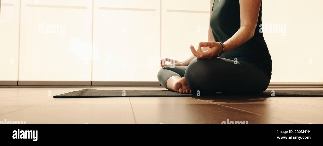 Seniorin meditiert während einer Hatha-Yoga-Sitzung. Unbekannte Frau, die eine Entspannungsübung macht, während sie in lockerer Pose sitzt. Reife Frau Prac Stockfoto