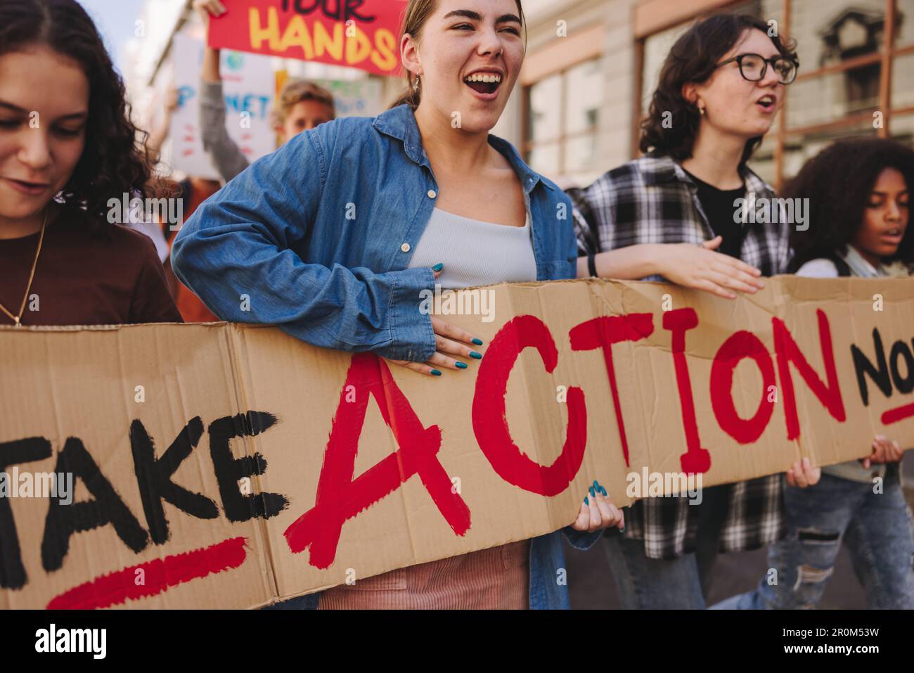 Globaler Klimaschutz. Lebhafte junge Menschen halten ein Banner und marschieren gegen den Klimawandel. Multikulturelle Jugendaktivisten, die für Clim kämpfen Stockfoto