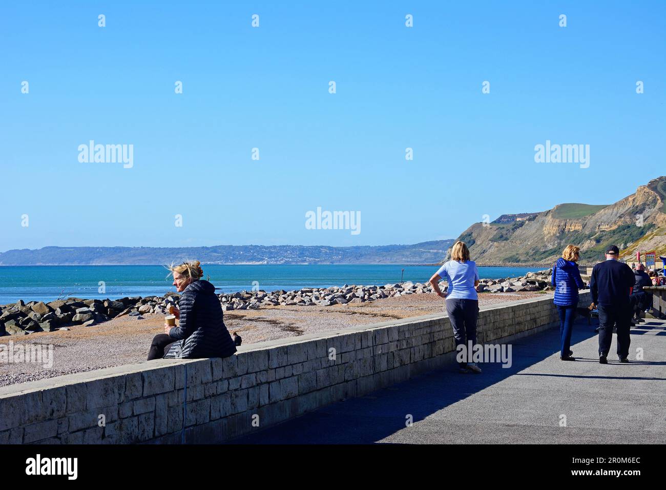 Touristen auf der Promenade mit Blick auf den Strand und die Jurassic Coast, West Bay, Dorset, Großbritannien, Europa. Stockfoto