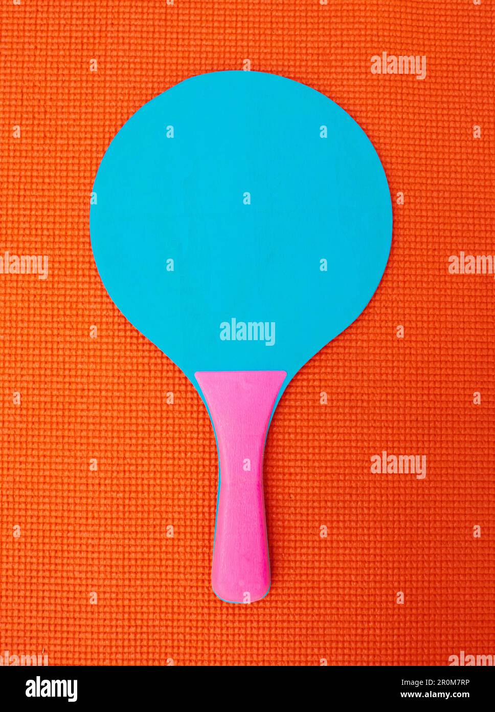 Sieht aus, als wäre es nur ich. Aufnahme eines Tischtennisschlägers aus einem hohen Winkel auf einem orangefarbenen Hintergrund in einem Studio. Stockfoto