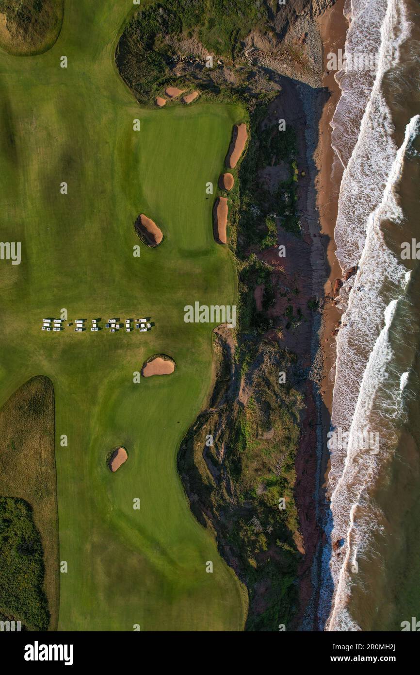 Ein malerischer Golfplatz in ruhiger Umgebung mit einem großen Gewässer, umgeben von üppigem Grün und sanften Hügeln Stockfoto