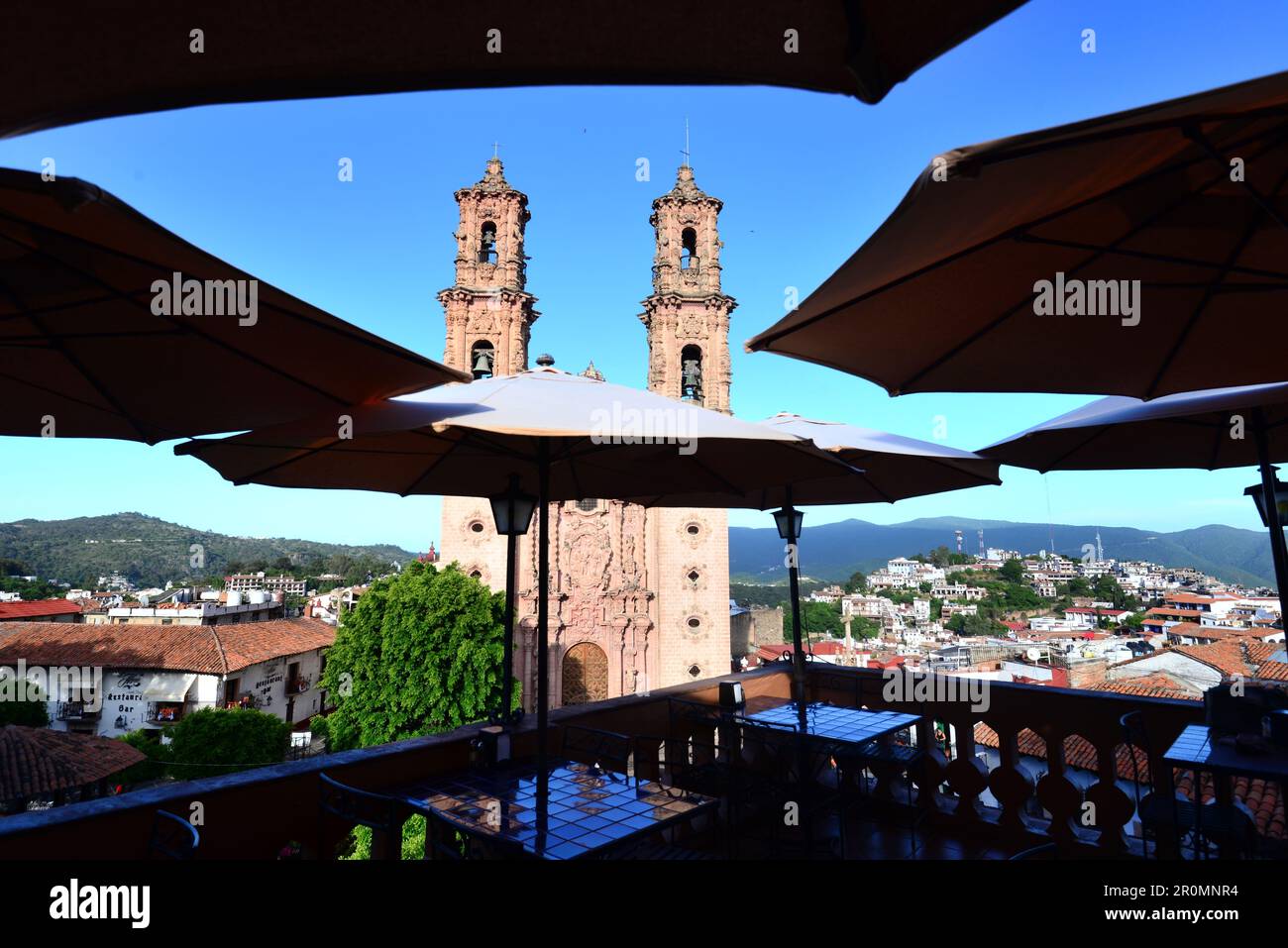 Blick vom Dach eines Restaurants mit Sonnenschirmen auf die Igleisia de Santa Prisca in der Altstadt von Taxco, Mexiko Stockfoto