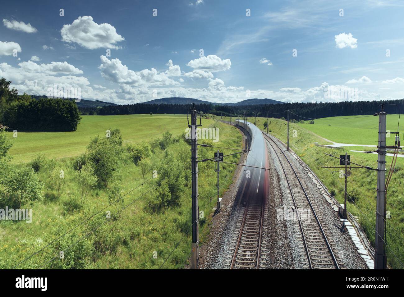 Drone Blick auf majestätische Landschaft der Zug Reiten entlang der Eisenbahn Umgeben von grünen Feldern und Bergen an sonnigen Tagen Stockfoto