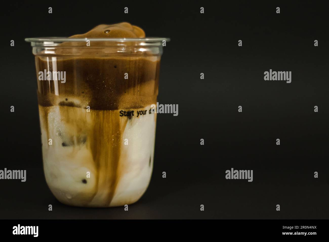 Eislatten-Kaffee in einem Plastikbecher auf schwarzem Hintergrund Stockfoto