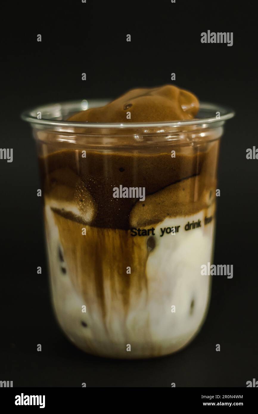 Eislatten-Kaffee in einem Plastikbecher auf schwarzem Hintergrund Stockfoto