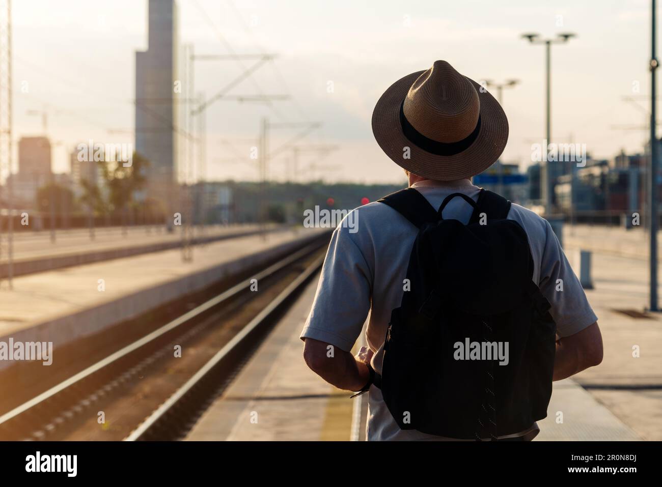 Ein Tourist mit Strohhut stand auf dem Bahnsteig und wartete auf den Zug. Stockfoto