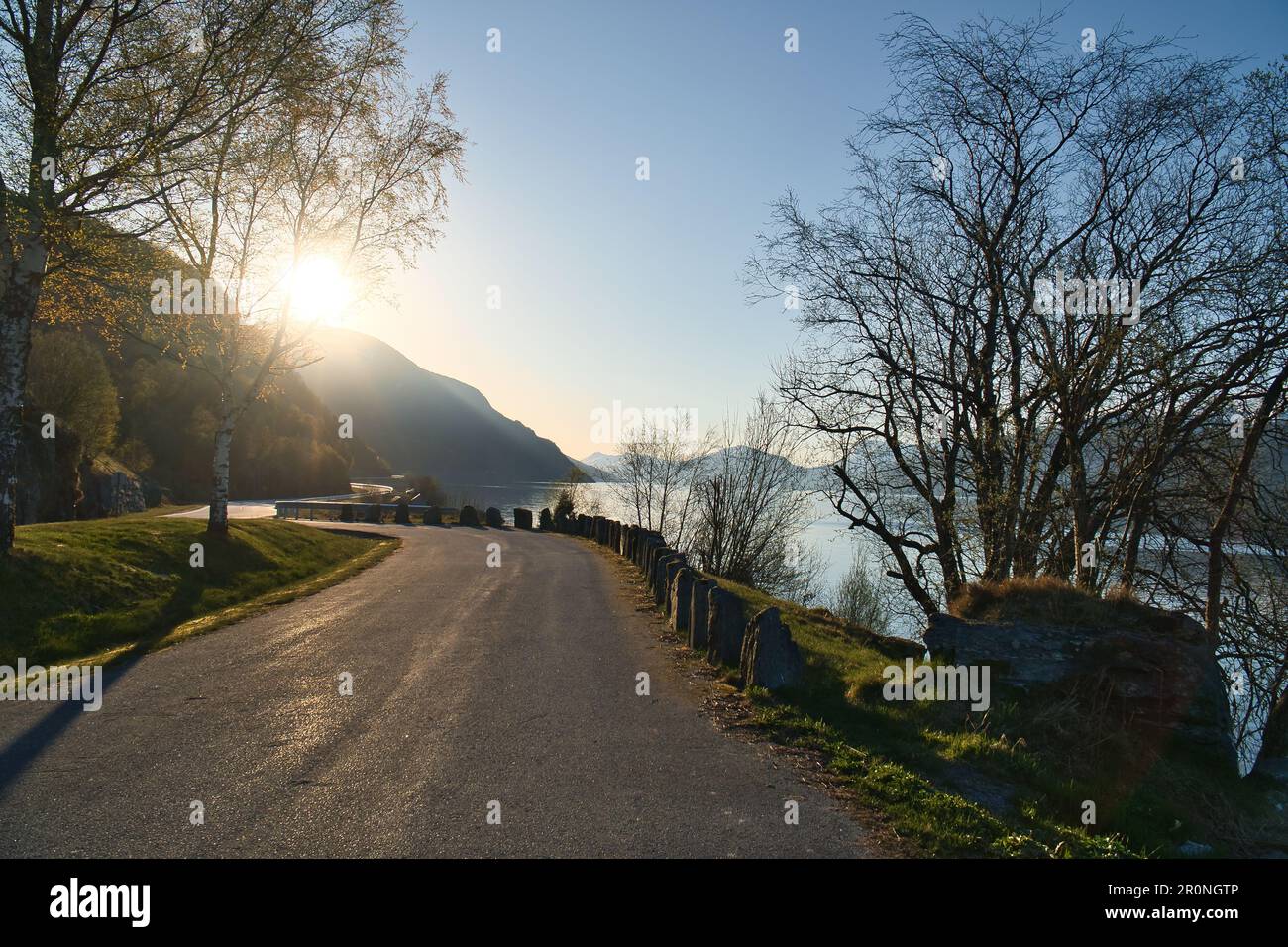 Parkplatz mit Blick auf die Straße, den Nordfjord und Bergen in Norwegen. Sonnenstrahlen fallen durch die Bäume. Landschaftsaufnahmen aus Skandinavien Stockfoto