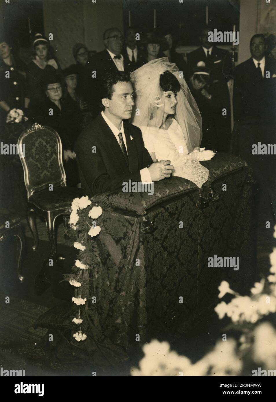 Braut und Groom in der Kirche auf den Knien, bereit Ja zu sagen, Italien 1960er Stockfoto