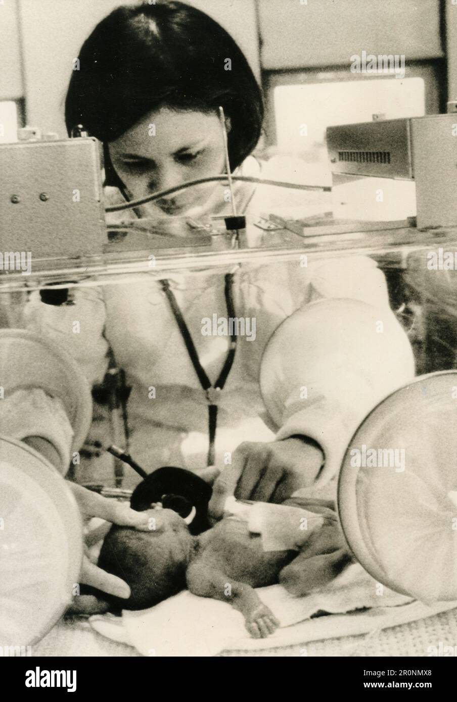 Die Krankenschwester kümmert sich um das kleine Neugeborene im Inkubator, 1960er Stockfoto