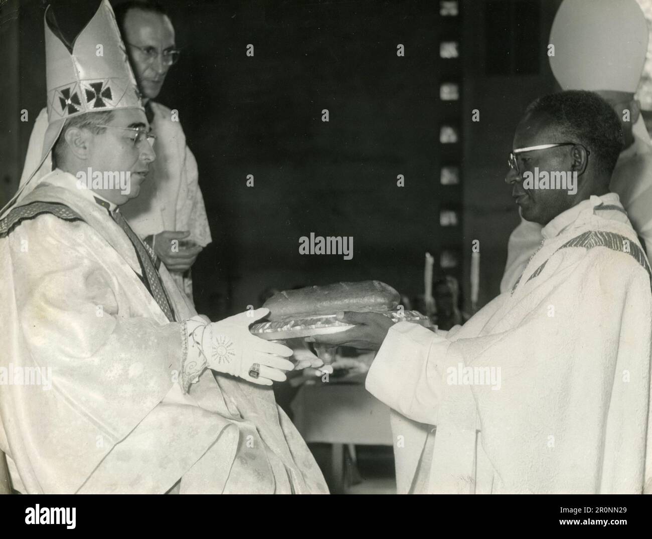 Der frisch geweihte Bischof carlos A. Lewis (links) überreicht seinem Nachfolger Reverend Albert Clavel Mendez, Erzbischof von Panama-Stadt, 1960er, zwei Brote Stockfoto