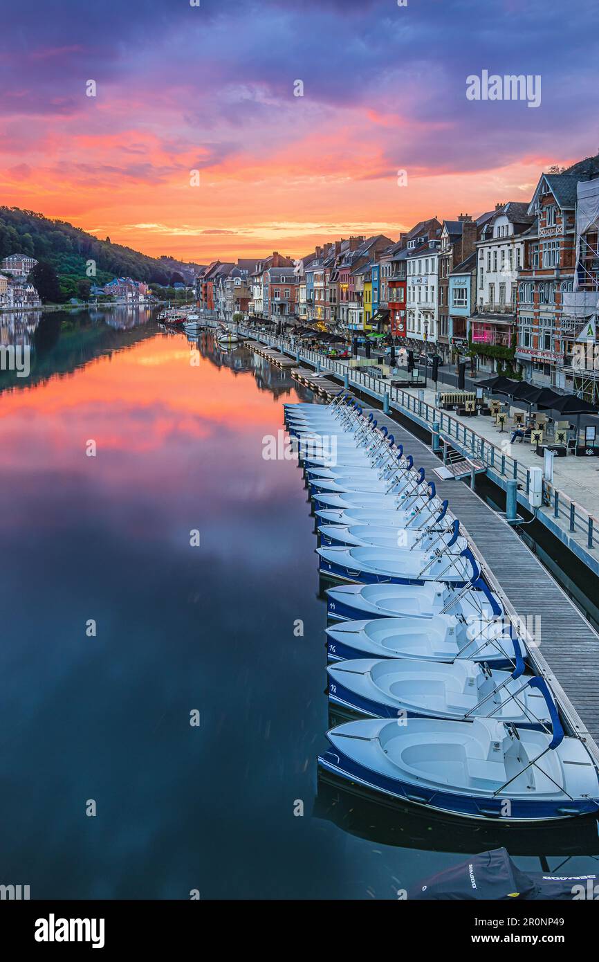 Farbenfroher Sonnenuntergang in Belgien der Stadt Dinant. Fluss Maas mit alten Häusern am Flussufer. Reflexion von Häusern und Sonnenuntergang auf der Wasseroberfläche. Stockfoto
