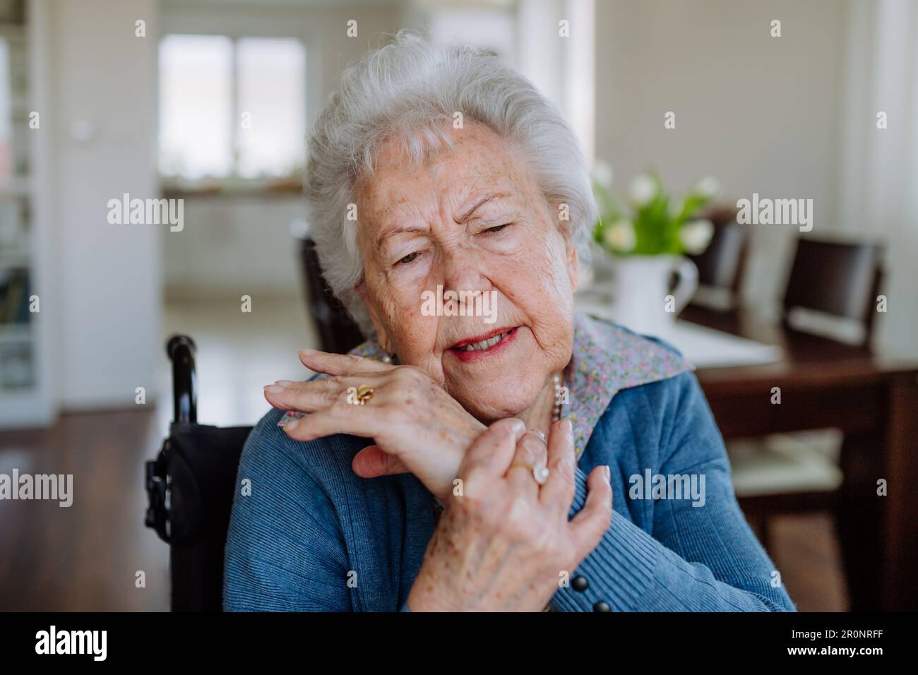Porträt einer Seniorin im Rollstuhl mit Schmerzen in der Hand. Stockfoto