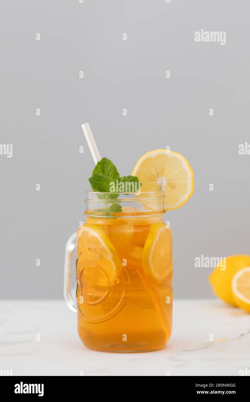 Ein Glas kalten Tee, Eiswürfel, Zitronenscheiben und einen Pfefferminzzweig. Kühle Sommergetränke. Stockfoto