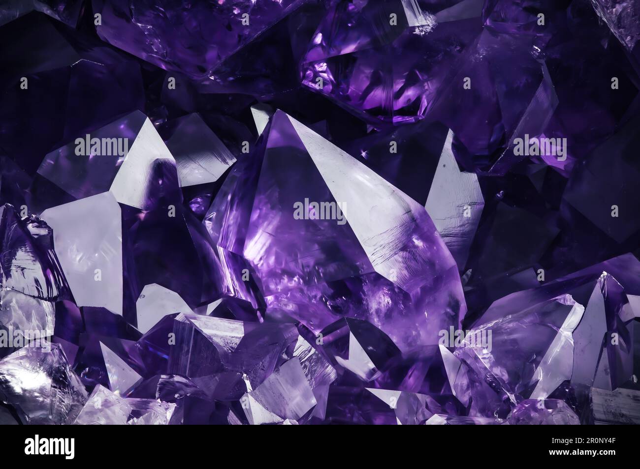 Amehtystischer violetter Kristall auf schwarzem Hintergrund. Texturhintergrund für Makrodetails. Nahaufnahme von rohem, unpoliertem Halbedelstein Stockfoto