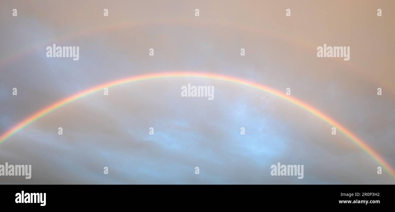 Doppelter Regenbogen in stürmischem Himmel. Dieses atemberaubende Naturphänomen wird Ihnen den Atem rauben Stockfoto