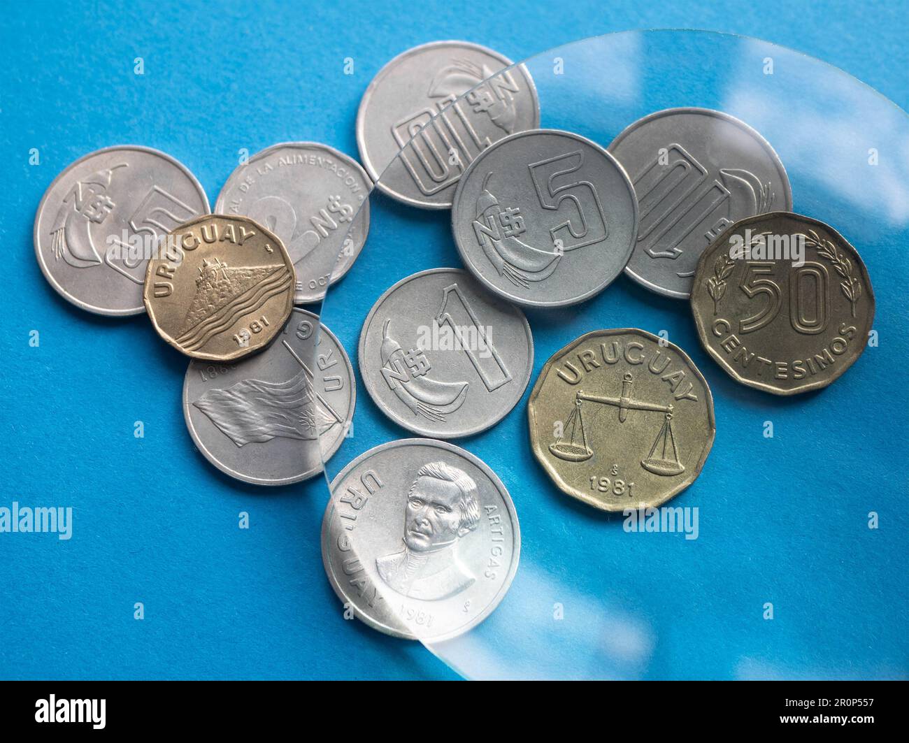 Nuevos Peso- und Centesimos-Münzen von Uruguay durch eine Lupe, selektiver Fokus. Nationale uruguayische Währung Stockfoto