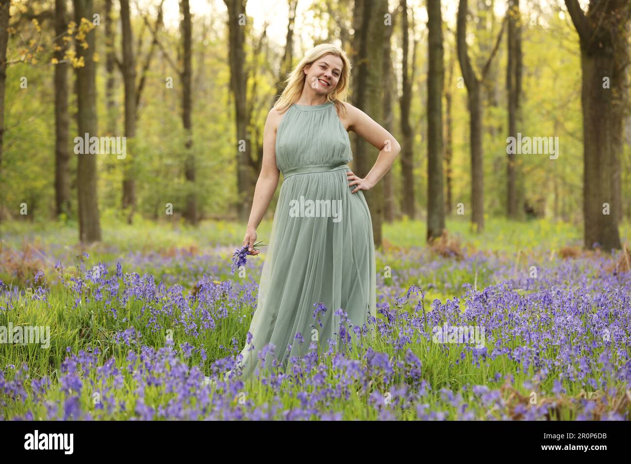 Eine Frau, die in einem blauen Holz steht und ein langes grünes Kleid trägt Stockfoto