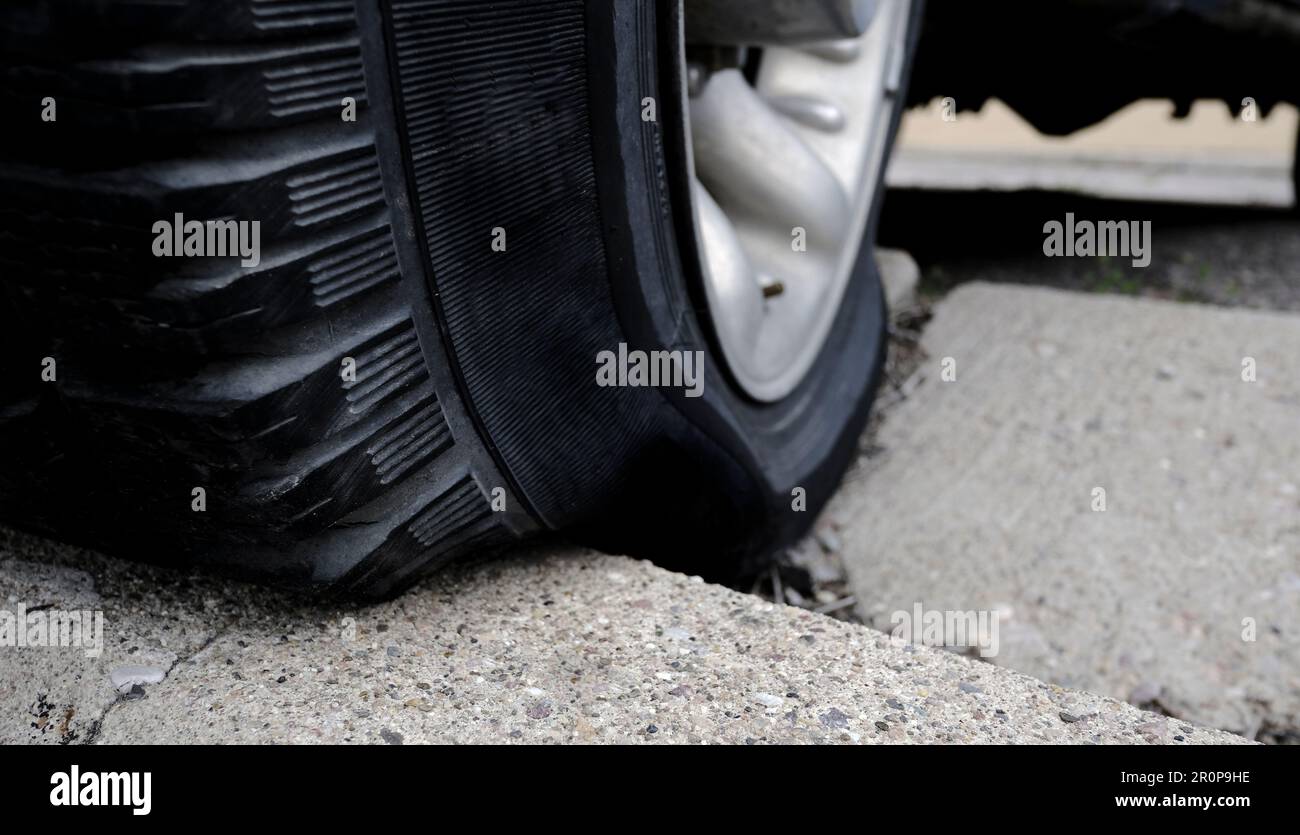 Ein defekter Reifen wurde aufgrund eines schlechten Parkplatzes auf den Bordstein gedrückt Stockfoto