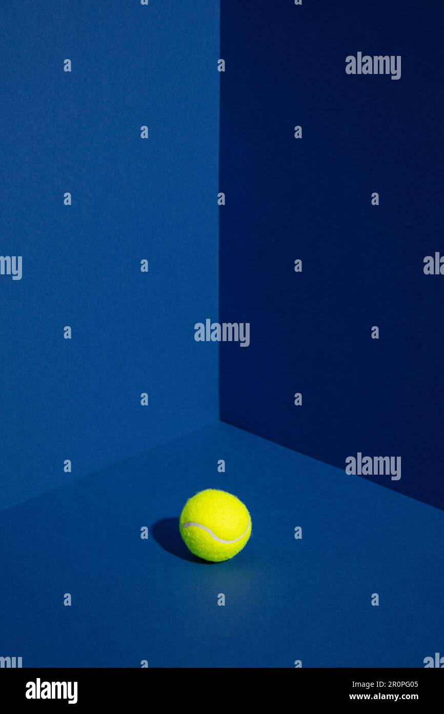 Tennisball in der Ecke der blauen Wände. Minimales kreatives Sportkonzept. Stockfoto