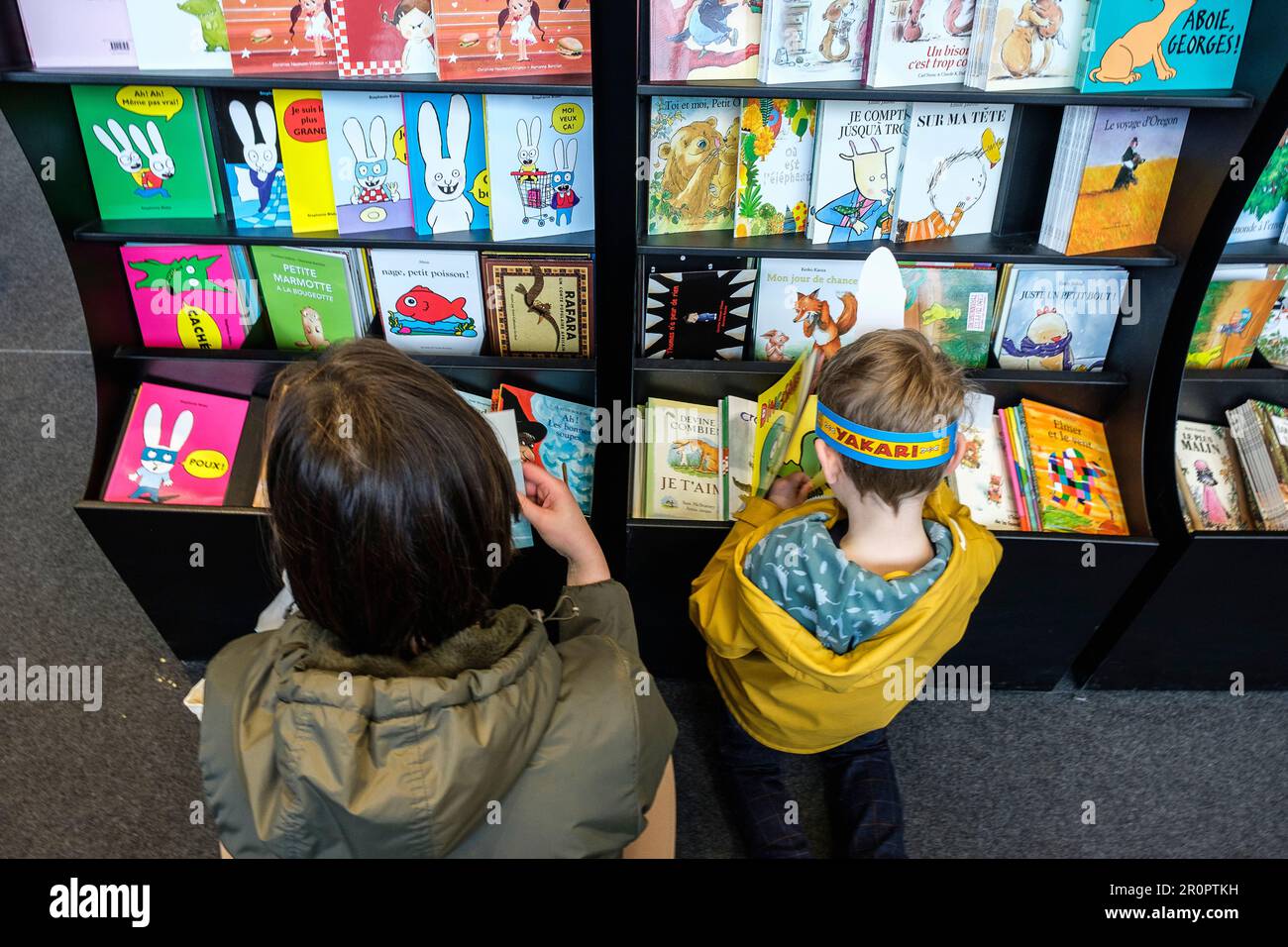 Foire du Livre de Bruxelles les gens se pressent autour des presentoirs 2023 Choisir un livre maman et enfant| Brussels Books fair 2023 - Picking a bo Stockfoto