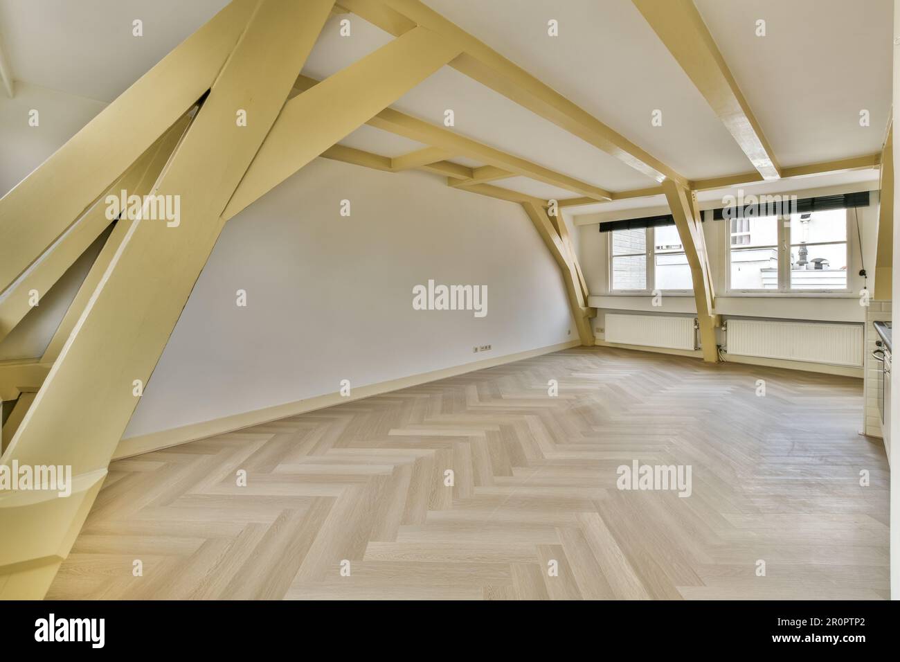 Ein leeres Zimmer mit Holzfußboden und weißen Wänden in der Gegend ist sehr geräumig, aber es ist schwer zu sehen, wie Stockfoto