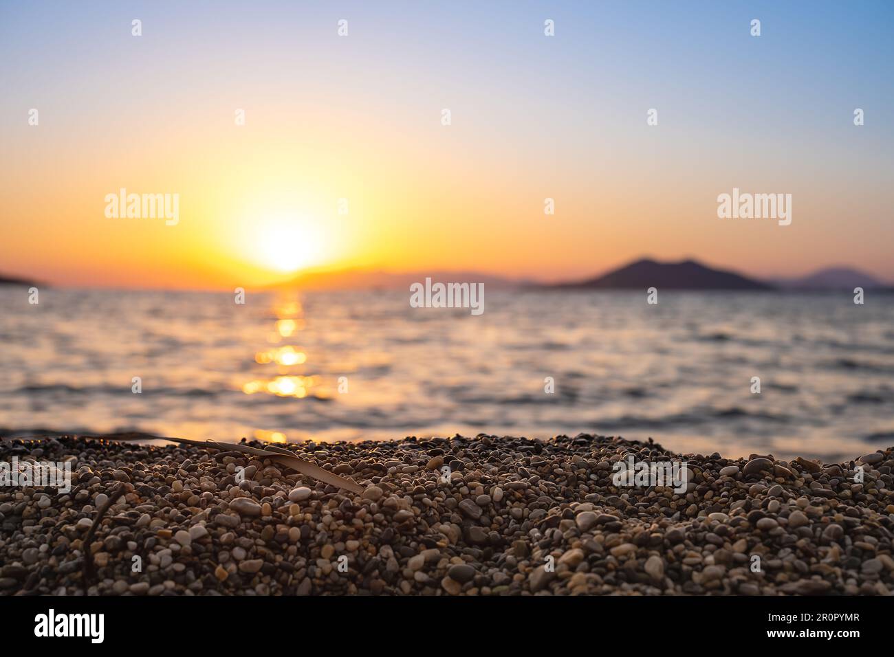 Sonnenuntergang über der Bucht, selektiver Fokus auf die Kieselsteine am Strand, verschwommener Hintergrund, Idee für Bildschirmschoner oder Werbung Stockfoto